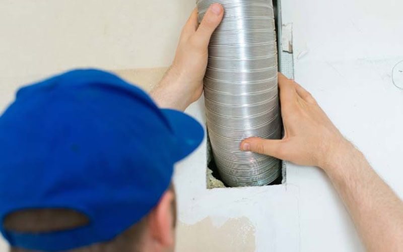 Man setting up ventilation system indoors. When Is It Time for a Split-System AC Replacement?