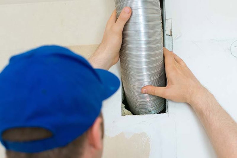 Man setting up ventilation system indoors. When Is It Time for a Split-System AC Replacement?