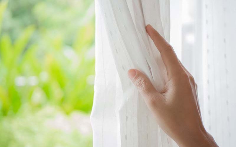 Hand holding white curtains