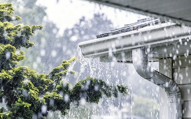 Drenching downpour rain storm water is overflowing off the tile shingle roof - streaming
