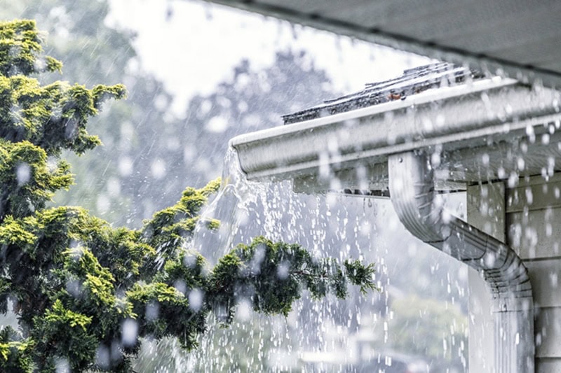Drenching downpour rain storm water is overflowing off the tile shingle roof - streaming