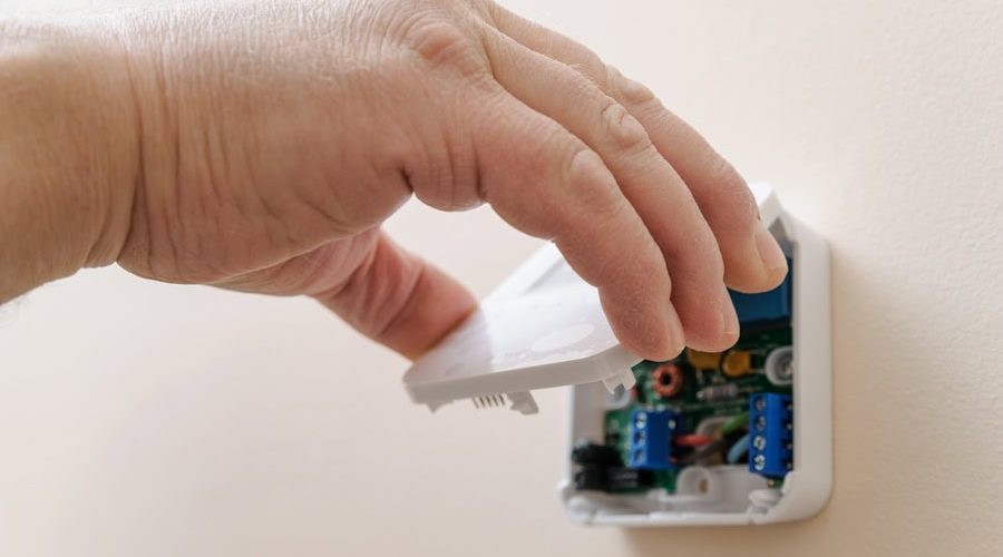 Installing a programmable room thermostat. Man's hand holding the lid of the device. Tips to Troubleshoot Your Thermostat