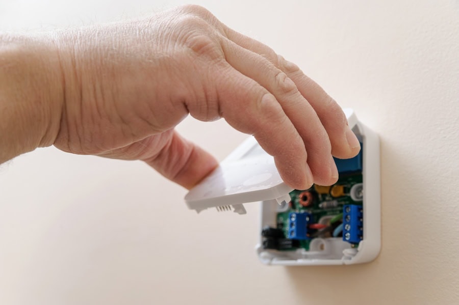 Installing a programmable room thermostat. Man's hand holding the lid of the device. Tips to Troubleshoot Your Thermostat