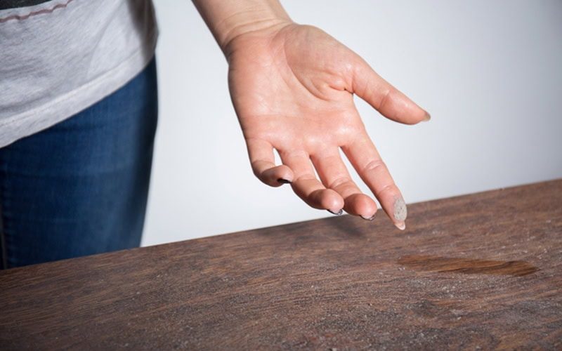 hand wiping dust off of desk