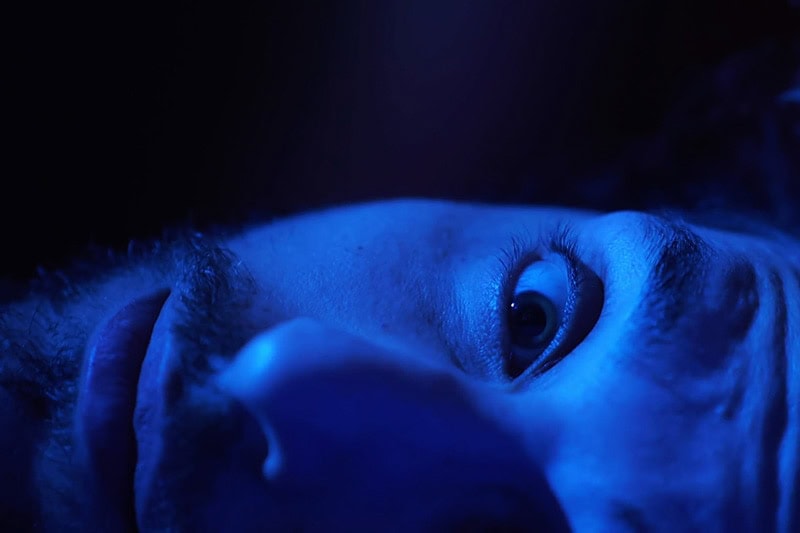 A close-up of a man lying awake in bed | Video - Is Your AC Making Scary Noises? | Call Us Today