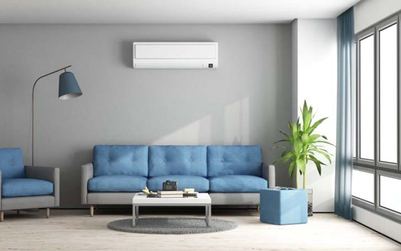 Ductless Mini Splits for Comfortable and Healthy Living. Blue and gray modern living room with sofa, armchair and air conditioner.