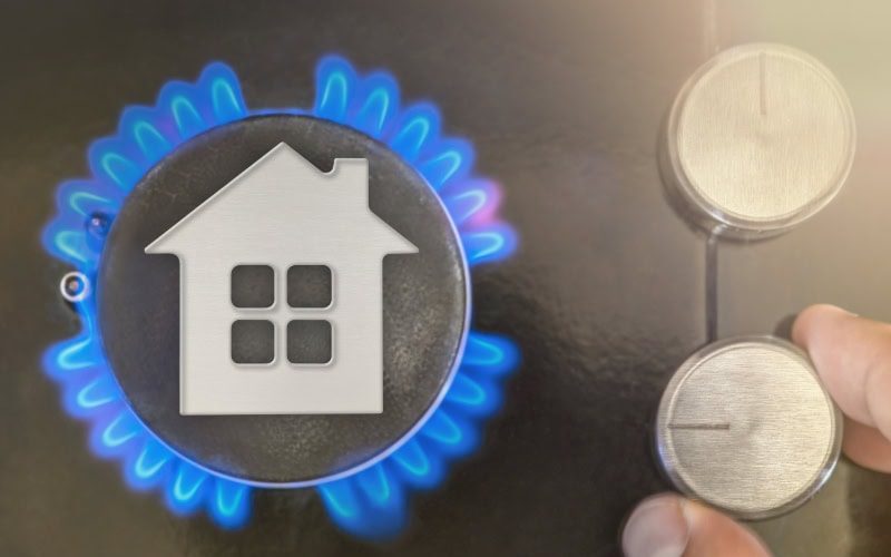 Heating season. The use of gas as heating at home in winter, the cold season. The concept, the model of the house stands near the flame of a gas boiler.