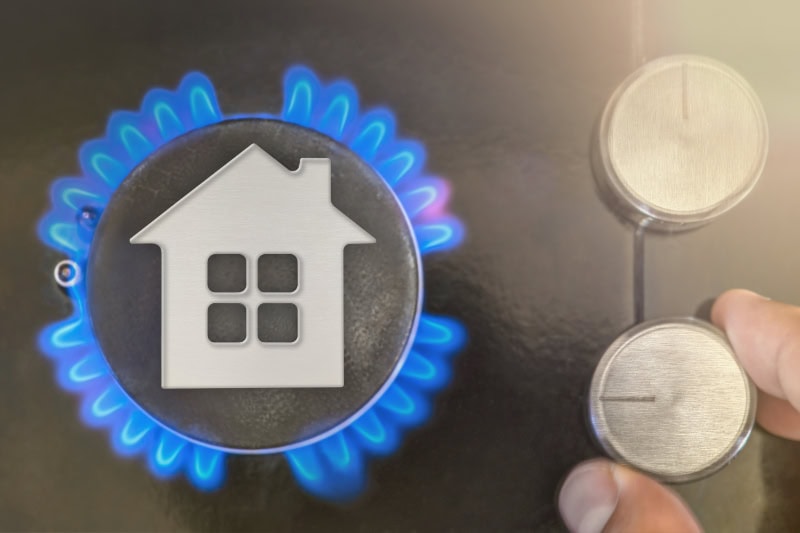 Heating season. The use of gas as heating at home in winter, the cold season. The concept, the model of the house stands near the flame of a gas boiler.