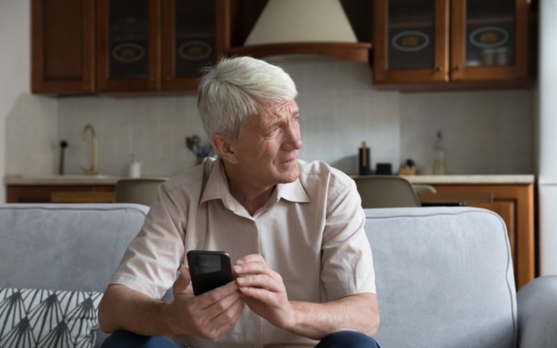 What’s That Smell Coming From My Furnace? Photo of a man sitting on his couch, looking out the window seemingly concerned.