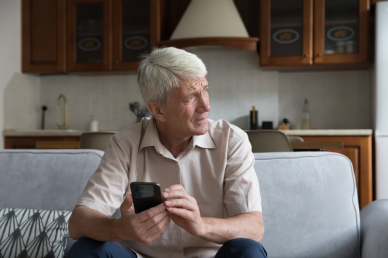 What’s That Smell Coming From My Furnace? Photo of a man sitting on his couch, looking out the window seemingly concerned.
