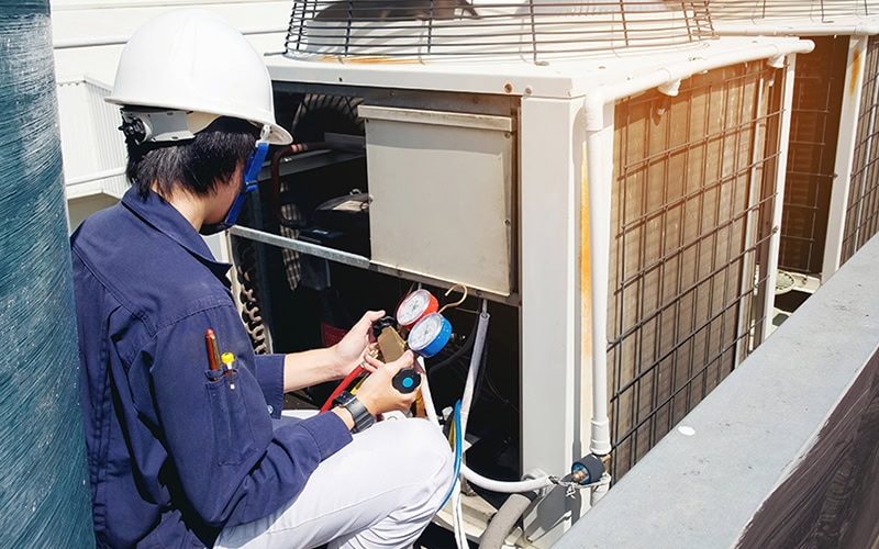 A technician working on a commercial air conditioner.