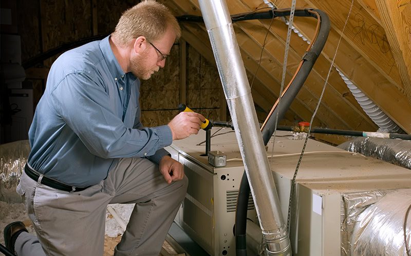 Furnace Maintenance and Winter Energy Saving Tips. Photo of a technician installing a heating system in a home.