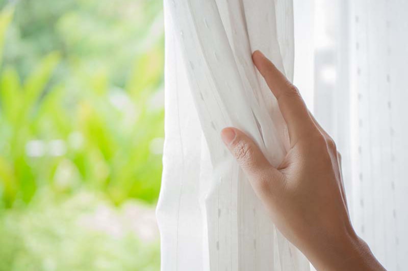 Hand holding white curtains