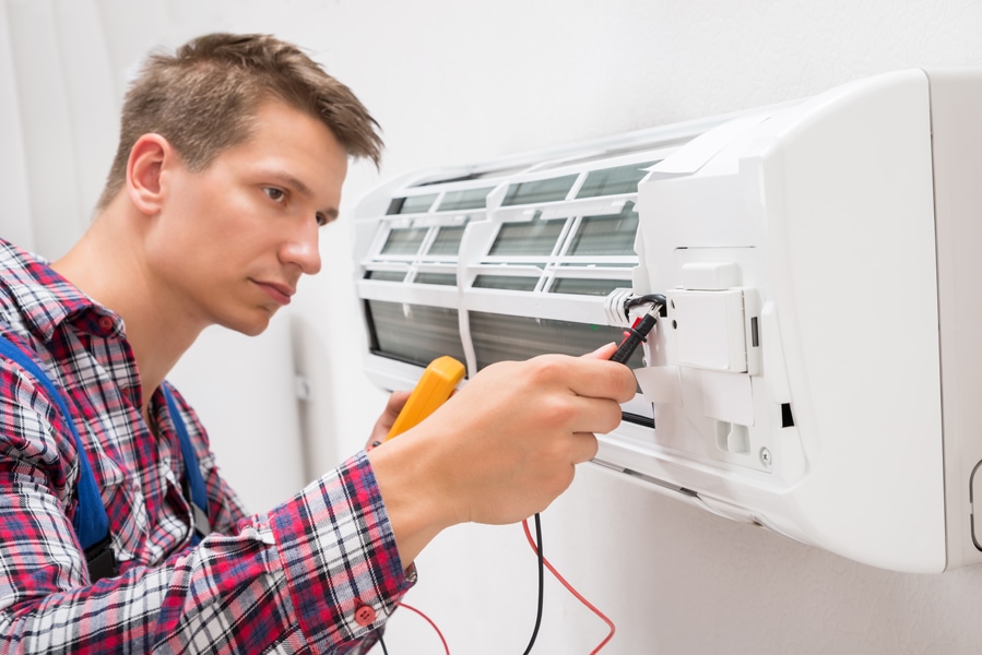 Male Technician Examining Air Conditioner With Multimeter. What You Need to Know for an HVAC Emergency